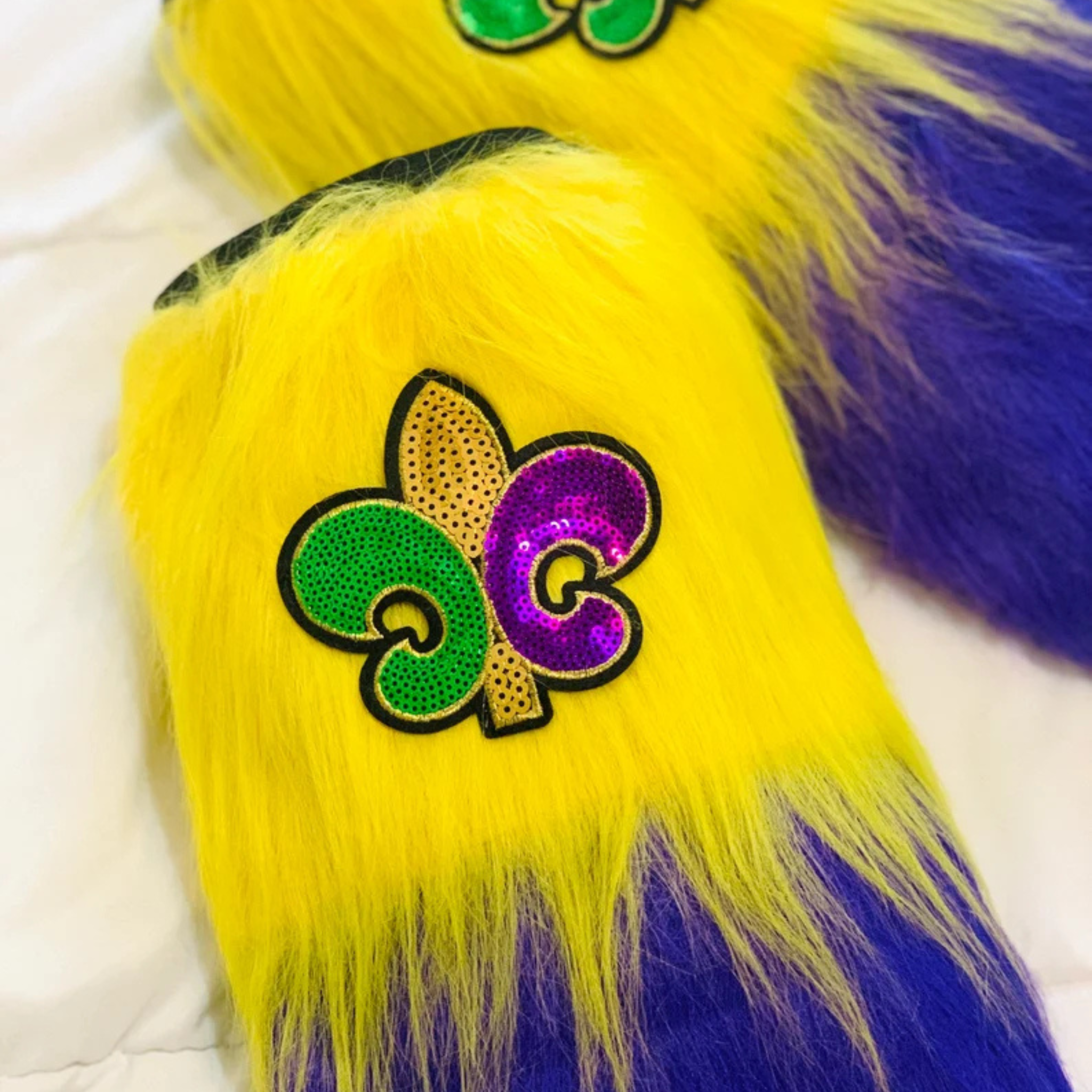 Mardi Gras Furry Leg Warmers with purple, green, and gold stripes, featuring a Fleur-de-Lis patch.